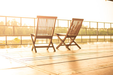 Fototapeta na wymiar Balcony view at sunset with wooden chairs. Interior design of resort at holiday travel