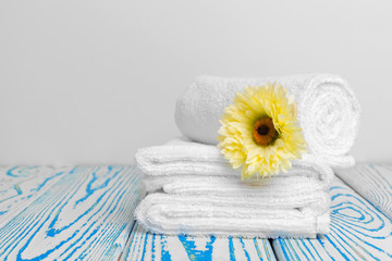 Fototapeta na wymiar clean soft towels with flower on wooden table