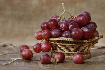 a bunch of red grapes on bamboo basket 