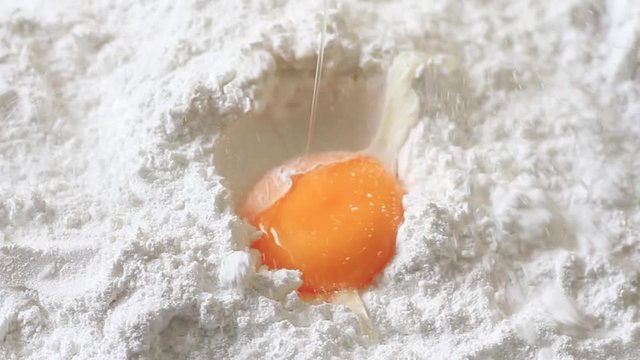 Egg falling on flour