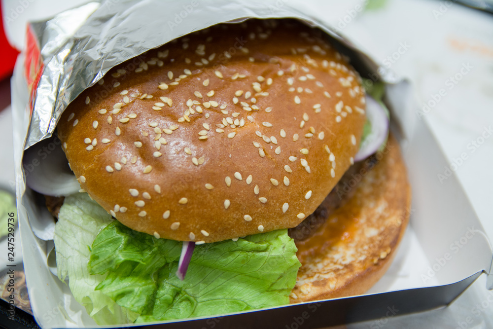 Wall mural close up of burger wrapped in foil paper on table