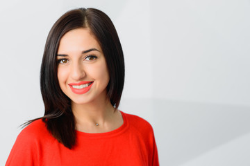 Fototapeta premium Beautiful cheerful optimistic confident brunette girl dressed in red with perfect smile