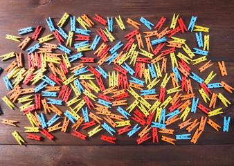 Red, orange, blue, yellow pegs on brown wooden background