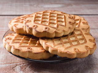 Cookies in a saucer on a brown wooden background