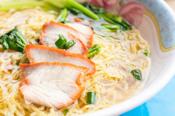 close up of barbecue red pork with egg noodles soup