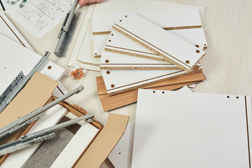The furniture assembler joins together the two parts of the ready-to-assemble furniture with cam lock connections and wooden dowel pin, flat pack furniture assembly service, snap-together joints