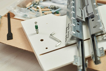 The furniture assembler joins together the two parts of the ready-to-assemble furniture with cam lock connections and wooden dowel pin, flat pack furniture assembly service, snap-together joints