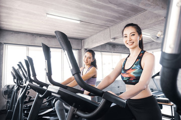 Fototapeta premium Attractive young women working out together on exercise bike at the gym.