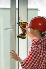 Woman using drill on window