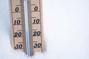 wooden thermometer in snow with freezing temperature copy space