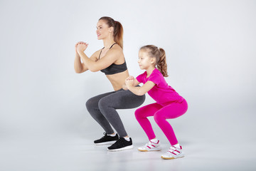 Female trainer and 10 years old girl are doing gym exercises