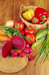 Appetizing vegetables. Tomatoes, radishes, cucumbers, carrots, peppers, eggplants, parsley on a wooden table