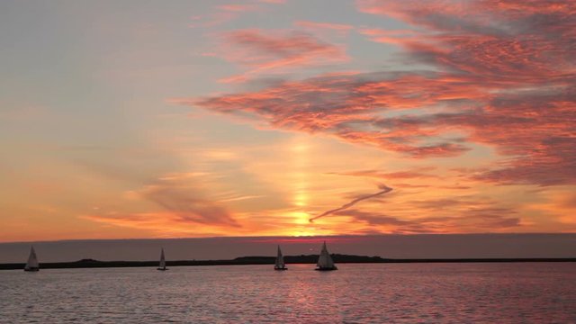 Dinghies sail at sunset on lake