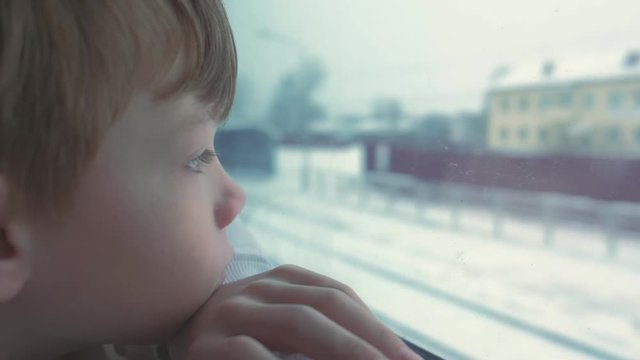 Boy is looking in window in moving train on winter landscape.