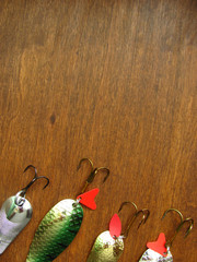 Four shiny artifician baits: details of fishing spinners down below on a wooden dark background...