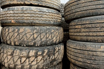 Stack of used worn muddy rubber tires, assorted tread wear patterns