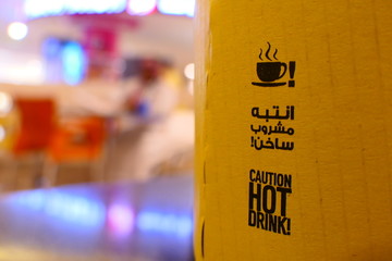 A coffee to go cup with the sign: CAUTION HOT DRINK