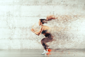 Side view of muscular focused brunette with ponytail and in sportswear jumping in front of brick wall in gym.