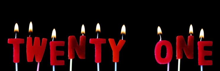 Twenty one spellt out in red birthday candles against a black background