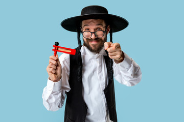 Portrait of a young orthodox Hasdim Jewish man with wooden Grager Ratchet at Jewish festival of Purim at studio. The purim, jewish, festival, holiday, celebration, judaism, pastry, tradition, cookie