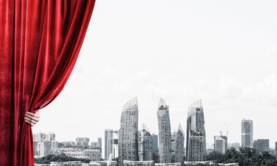 Modern business cityscape behind curtain opened by businessman hand