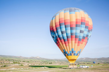 Fototapeta na wymiar colourful hot air balloon landing on a truck in a field on a sunny day for transportation 