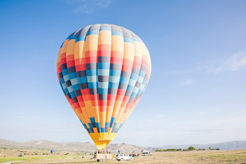 colourful hot air balloon landing on a truck in a field on a sunny day for transportation 