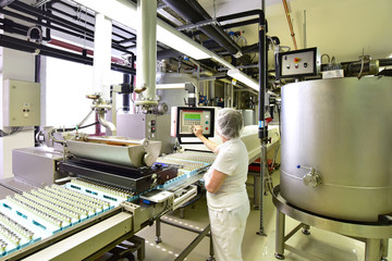 Frau bedient Maschine in der Lebensmittelindustrie - Fliessband mit Pralinen in Fabrik Automatisierung // Woman operates machine in food industry - assembly line with chocolates in factory automation