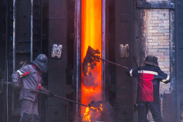 Workers of the coke oven throw the remnants of hot coke into the coke battery oven - obrazy, fototapety, plakaty