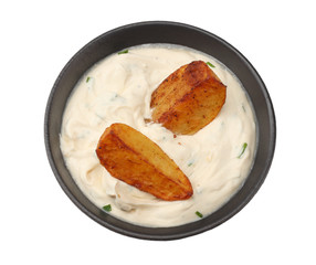 Fried potato wedges with garlic sauce in black bowl isolated on white background. top view.
