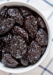 Full bowl of dry prunes, overhead view. Flat lay, from above, top view.