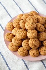 Almond cookies on pink plate on cloth, side view. Close-up.