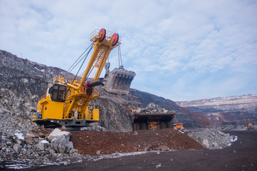 Excavator in the quarry loads the dumper with iron ore. Loading in winter