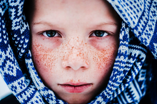Portrait of boy with freckles wrapped in scarf 