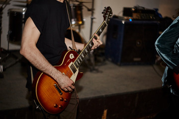 Musician in black t-shirt plays on the electric guitar