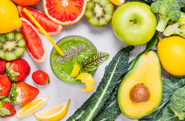 Fruits and vegetables vitamins detox drink.Green healthy smoothie in glass top view on white marble table.