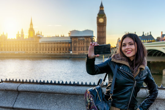 Attraktive Touristin in London macht ein Selfie Foto von sich vor dem Big Ben Turm bei Sonnenuntergang