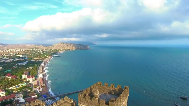 Aerial cinematic flight video: Genoese fortress in Sudak, Crimea. Consular Pirates castle and fortification wall on mountain. Fort wall of upper tier to coastline Black sea city Sudak Old Kaffa.