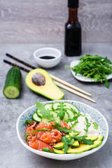 Salmon poke with avocado, arugula and cucumber in a bowl