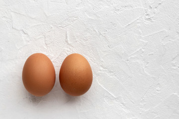 Two fresh eggs on white textural background with egg's shadow