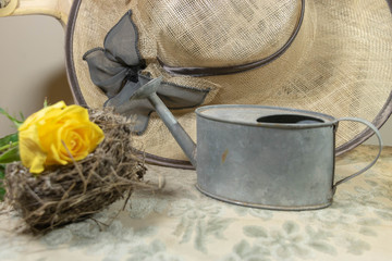 Retour du printemps, chapeau de paille rose jaune nid d'oiseau et arrosoir pour aller au jardin