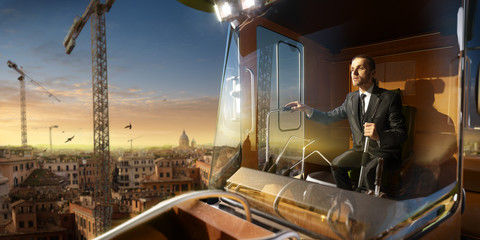 businessman operator crane in action . He sit a top in crane cabin and working. Around beautiful sunset
