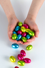 Cupped hands holding small easter eggs spilling onto surface
