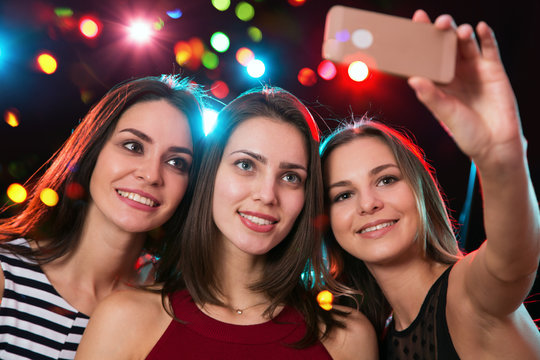 Smiling girls taking selfie in a night club