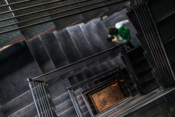 A man walking up the square steel stairwell - Powered by Adobe