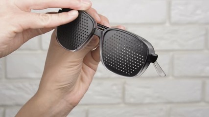 Looking at pinhole glasses. Obscura glasses in female hands.