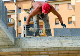 masonry worker make concrete wall by cement block and plaster at construction site
