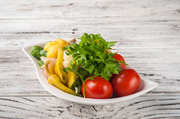 Fermented food in a plate on a white textural wooden table. Cucumbers, zucchini, garlic, marinade, tomatoes, cabbage, ramson, parsley. National Russian food pickles in brine close up and copy space