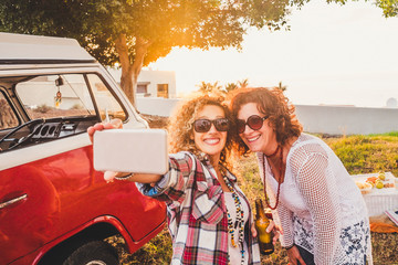 Nice attractive couple of middle age woman travel together with old red van vintage and take selfie with modern phone during outdoor picnic leisure activity - sunny day of summer vacation