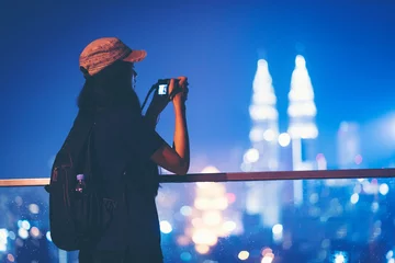 Papier Peint photo Lavable Kuala Lumpur Travel and technology. Young woman taking photo with her smartphone of Petronas Twins Towers in Kuala-Lumpur at evening